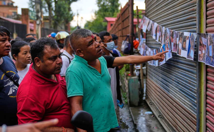 People look at photographs of people killed in flash floods displayed outside a government hospital to help relatives identify the victims in Kathmandu, Nepal