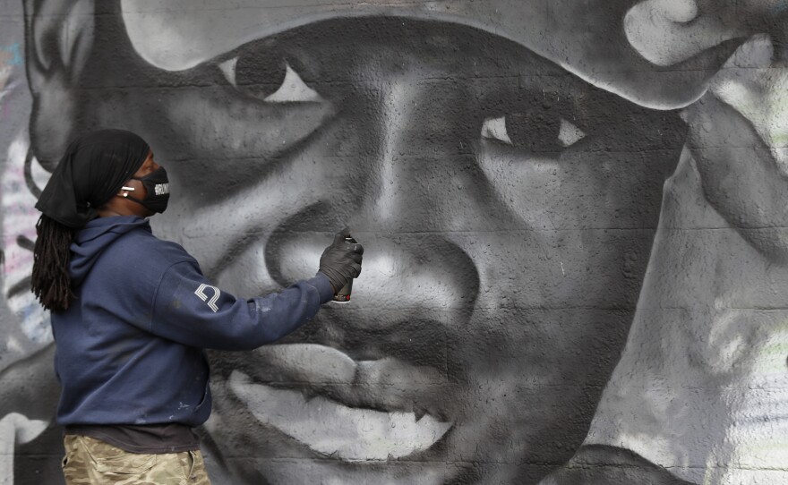 Theo Ponchaveli paints a mural of the likeness of Ahmaud Arbery in Dallas earlier this month. Arbery's killing in February in Georgia ignited anger and protests.