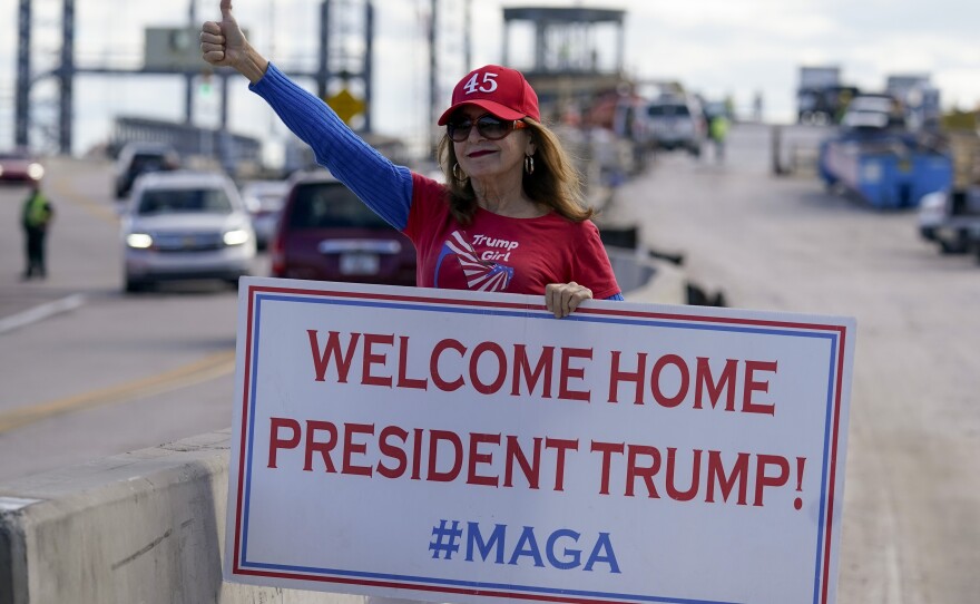 A supporter of former President Donald Trump waits for the motorcade on the road to Mar-a-Lago, Trump's Palm Beach estate, as he returned home on the day of President Biden's inauguration.