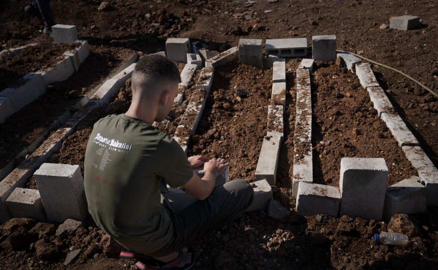 A young man sits by the fresh graves of the two teenagers and one 20-year-old killed in the recent Israeli drone strike in Jenin.