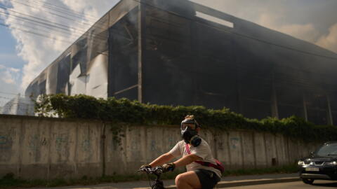 A local resident wears a gas mask as he rides a bicycle past a partially destroyed warehouse after a Russian drone attack in Brovary on the outskirts of Kyiv, Ukraine, Friday, Sept. 4, 2026.