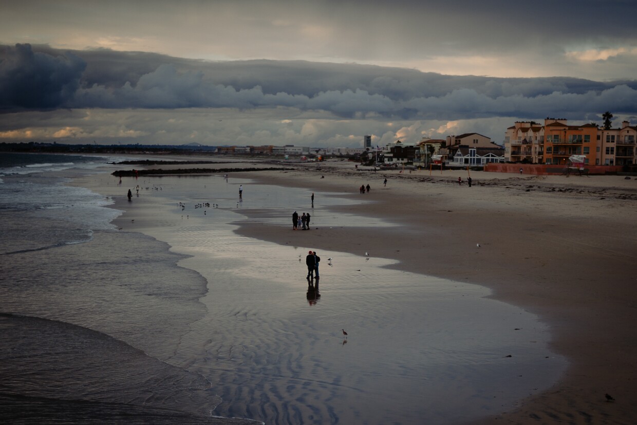 People walk in the waves in Imperial Beach, Sept. 30, 2023.