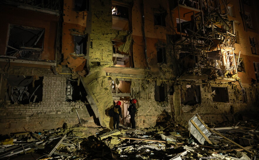 Rescue workers walk in front of a residential building damaged by a Russian airstrike in Zaporizhzhia, Ukraine, on Saturday.
