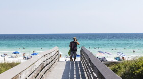 A beachgoer uses the boardwalk at Ed Walline Regional Beach Access off Scenic Highway 30A in Santa Rosa Beach, Fla. This stretch of the Gulf Coast has become "ground zero" in a battle between private property rights and public beach access.