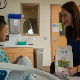 Elsa Morales-Roth (right), executive director of the Emilio Nares Foundation, hands a snack bag to a child recovering from chemoin this undated photo. 
