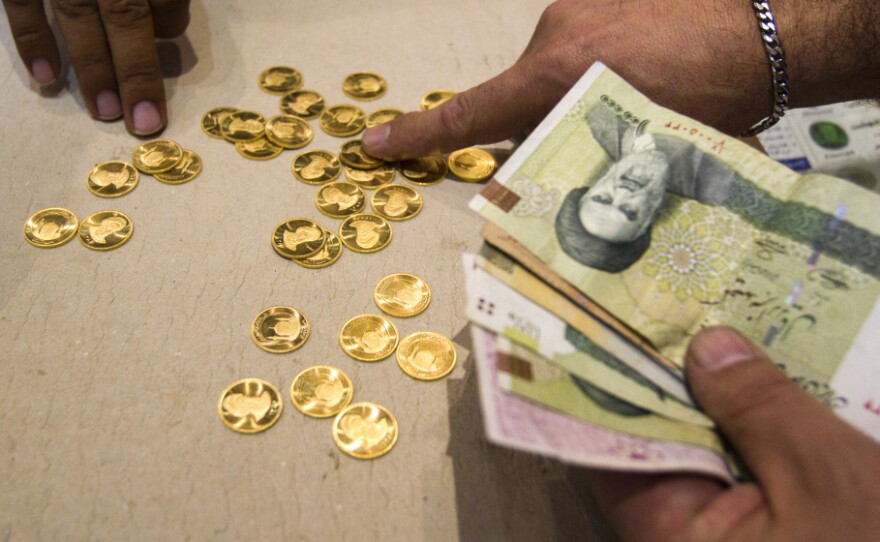A customer buys Iranian gold coins at a currency exchange office in Tehran. The loss in the rial's value has led Iranians to take their money out of the country — even by speedboat across the Persian Gulf.