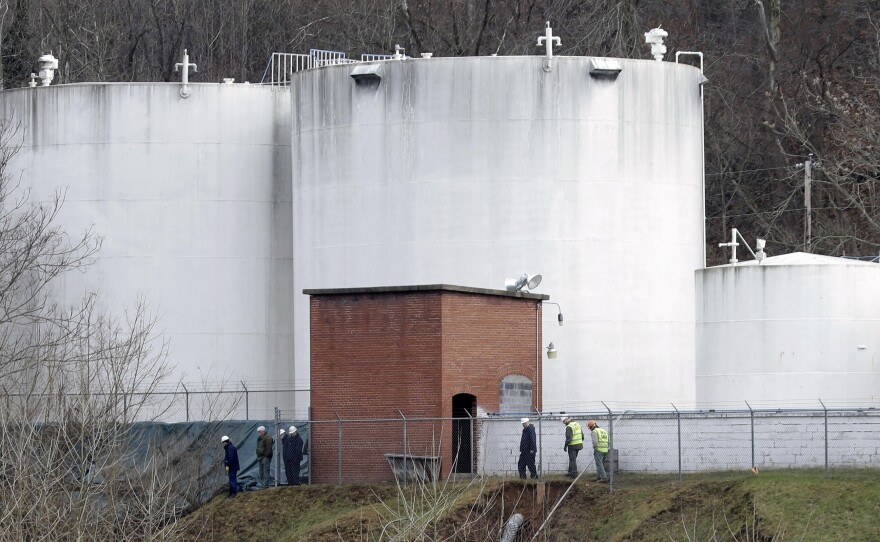 Workers inspect an area around storage tanks where a chemical leaked into the Elk River at Freedom Industries' storage facility in Charleston, W.Va., in January 2014.