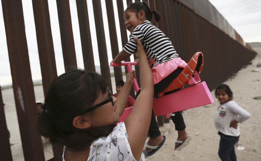 A set of pink seesaws allowed people to share some fun along the U.S.-Mexico border wall this week. Here, a woman helps her little girls ride the seesaw that was installed near Ciudad de Juarez, Mexico.
