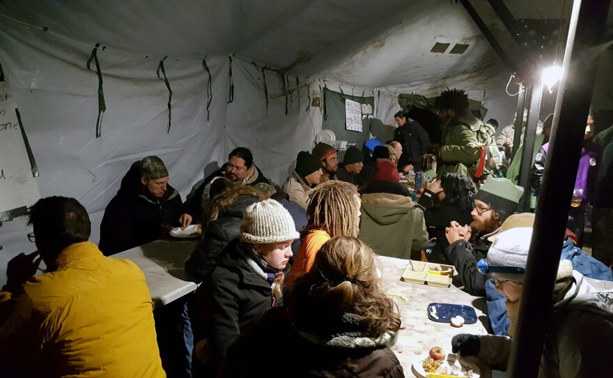 People at the Oceti Sakowin Camp enjoy a meal inside a tent that serves as a dining hall. Oceti Sakowin is the largest of several camps housing demonstrators against the Dakota Access Pipeline.