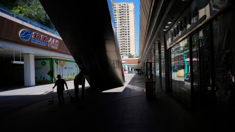 A worker collects trash in a partially shuttered Evergrande commercial complex, on the day Hong Kong Stock Exchange delisted the Chinese property developer China Evergrande, in Beijing, China, Aug. 25, 2025.