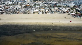 Workers in protective suits clean the contaminated beach after an oil spill in Newport Beach, Calif., on Wednesday, Oct. 6, 2021.