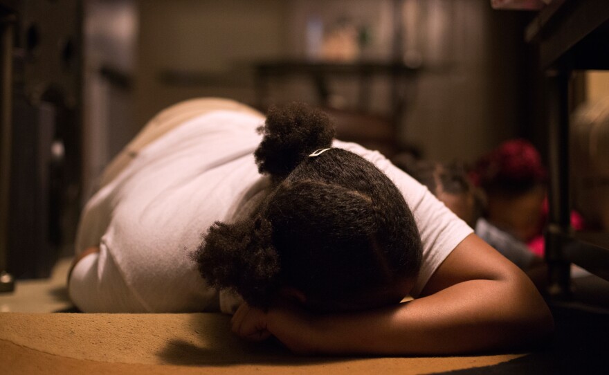 Anajah Hicks, 13, demonstrates the position she's been taught to take when she hears gunshots. Her mom and grandmother make sure the teen and her siblings practice getting on the floor quickly to stay safe.