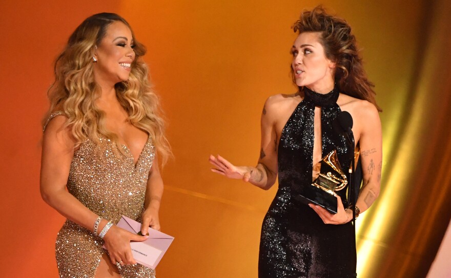 Miley Cyrus accepts the best pop solo performance award for "Flowers" from Mariah Carey on stage during the 66th Annual Grammy Awards.