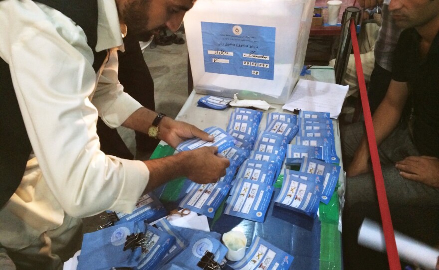 An Afghan election worker examines ballots to check for similar handwritten marks that would suggest ballot-stuffing fraud.