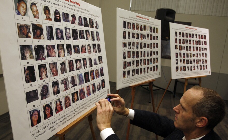 Frank Stoltze, a reporter for Southern California Public Radio, takes a photo of the 180 photographs and video stills of 160 women displayed at a press conference. The photos and stills were found in the Grim Sleeper's possession.
