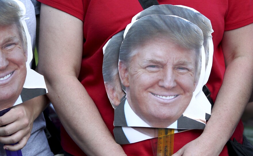 A woman holds signs depicting the head of Republican presidential candidate businessman Donald Trump as she waits to enter the auditorium to hear him speak in New Hampshire.
