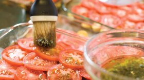 A pan of sliced tomatoes brushed with olive oil from AMERICA'S TEST KITCHEN. Host Christopher Kimball and the test kitchen team explore delicious recipes and ingredients, new cooking technologies and the science of food to help home chefs find success in the kitchen.