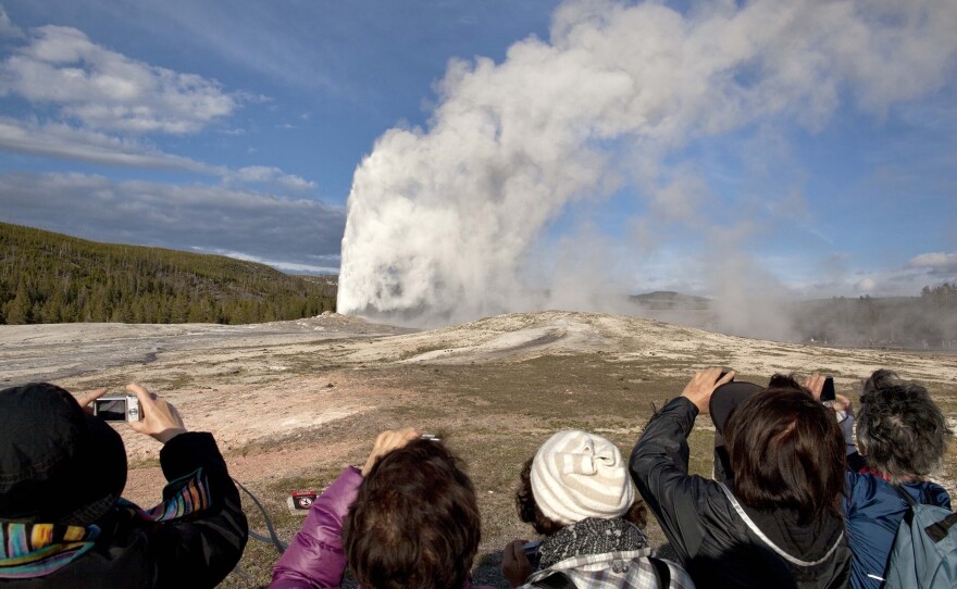 Tourists photograph Old Faithful geyser erupting in 2011 in Yellowstone National Park, Wyo.