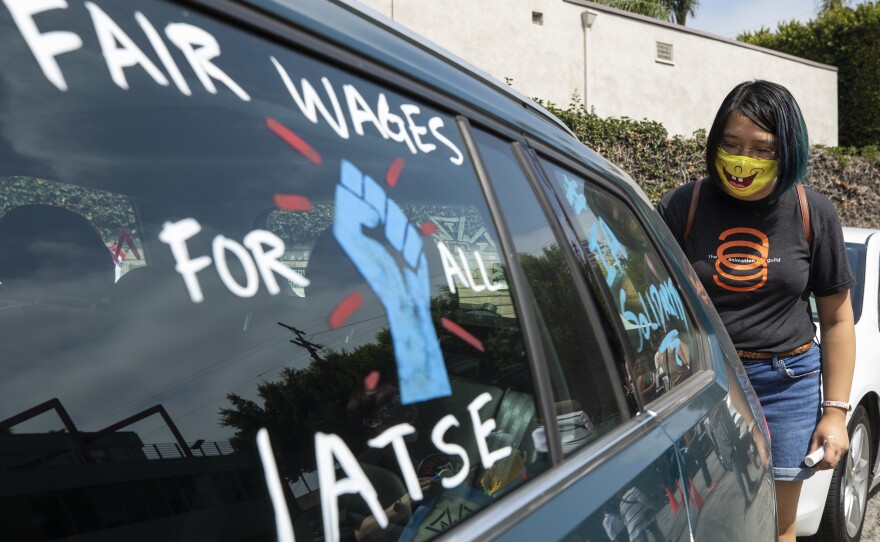 Crystal Kan, a storyboard artist, draws signs on cars of IATSE union members during a rally in Los Angeles in September.