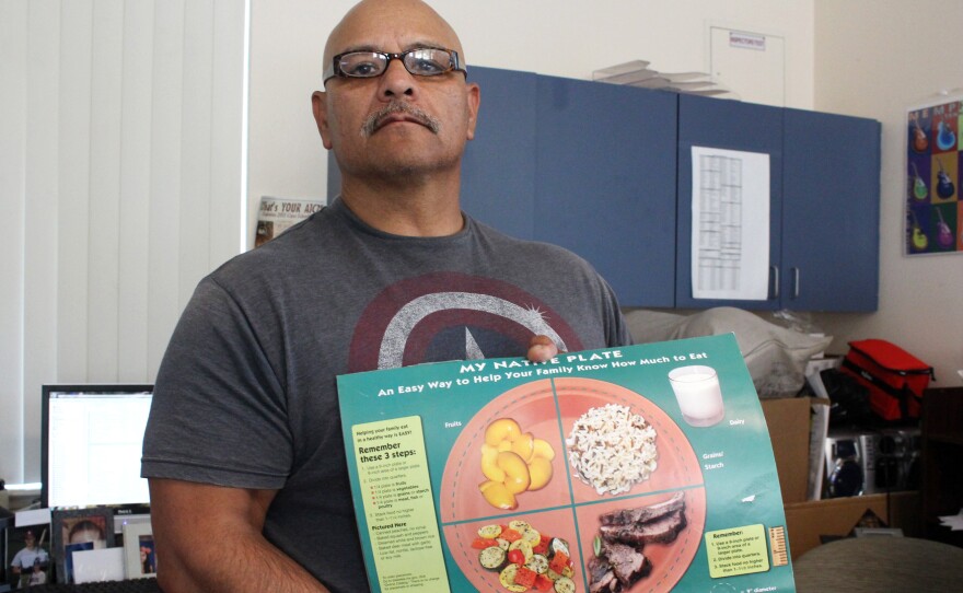 Gonzales shows off a food guide for patients in the clinic's diabetes prevention program. He tells clients to stay away from processed foods and "get off the couch."