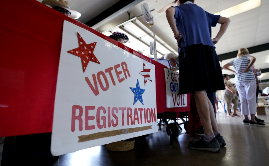 People stand near a voter registration table at a 2022 event in Fredericksburg, Texas.