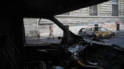 A woman walks past burned-out cars after a quiet night Monday under curfew, the first since weekend protests over the cost of living turned into rioting and looting across France, in Paris, Tuesday, Oct. 20, 2026.