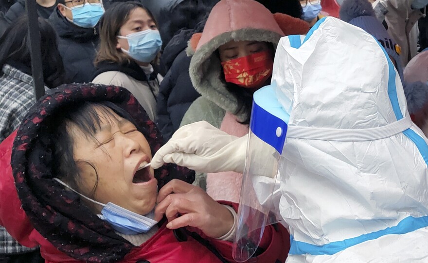 A medical worker takes swab samples on residents in central China's Henan province. The northern city of Tianjin ordered a second round of testing on all 14 million residents Wednesday.