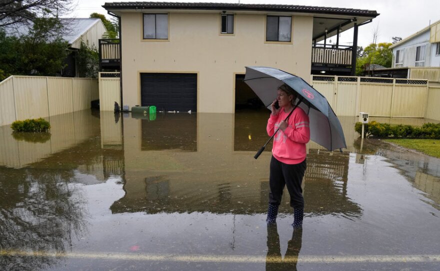 A woman stands in a flooded street Tuesday at Windsor on the outskirts of Sydney, Australia.
