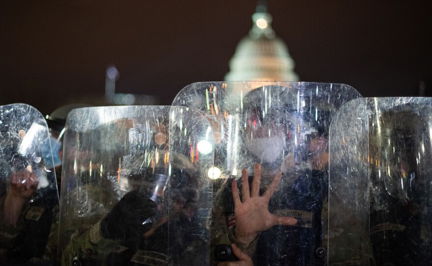 National Guard troops stand behind shields as they clear a street from protesters outside the U.S. Capitol on Jan. 6.