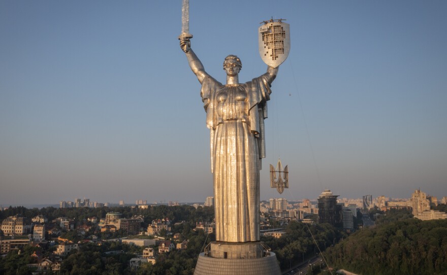 Workers install the Ukrainian coat of arms on the shield in the hand of the country's tallest stature, the Motherland Monument, after the Soviet coat of arms was removed, in Kyiv, Ukraine, Sunday, Aug. 6, 2023. Ukraine is accelerating efforts to erase the vestiges of centuries of Soviet and Russian influence from the public space.