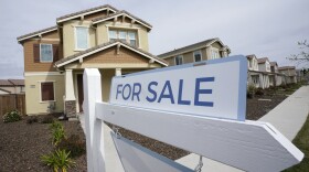 A for sale sign is posted in front of a home in Sacramento, Calif., in 2022.