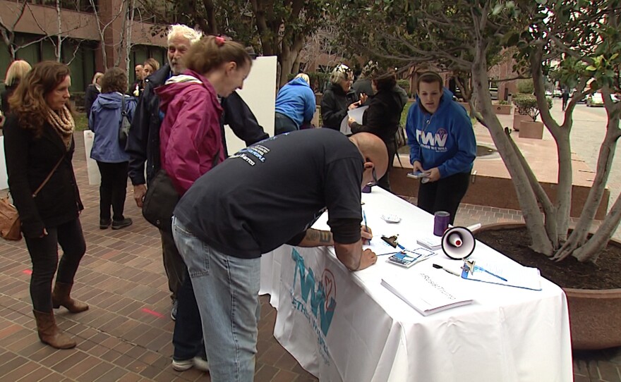 People sign a petition outside U.S. Sen. Dianne Feinstein's downtown San Diego office. The gathering is part of the organizing effort for the progressive coalition Indivisible, Feb. 7, 2017.
