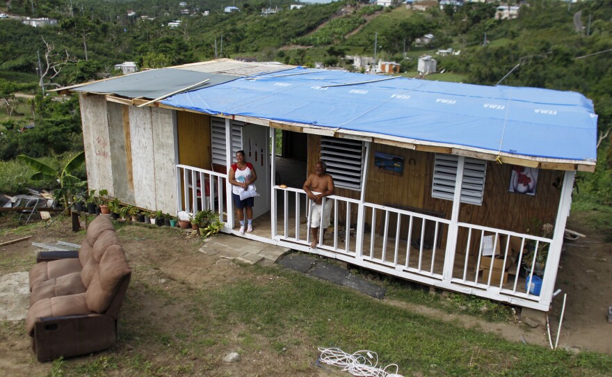 José Ramón Sierra Meléndez and his wife Felicita Garcia stand on their porch of their recently rebuilt house. Meléndez received the tarp and a couple of boxes of water from one passing FEMA truck.