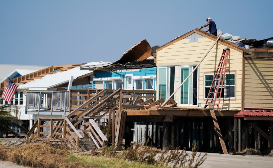 A man works on the roof of a storm-damaged house on Sept. 4 after Hurricane Ida swept through Grand Isle, La. A new poll finds that two-thirds of Americans say if their home is hit by an extreme weather event they'd rather rebuild than relocate.