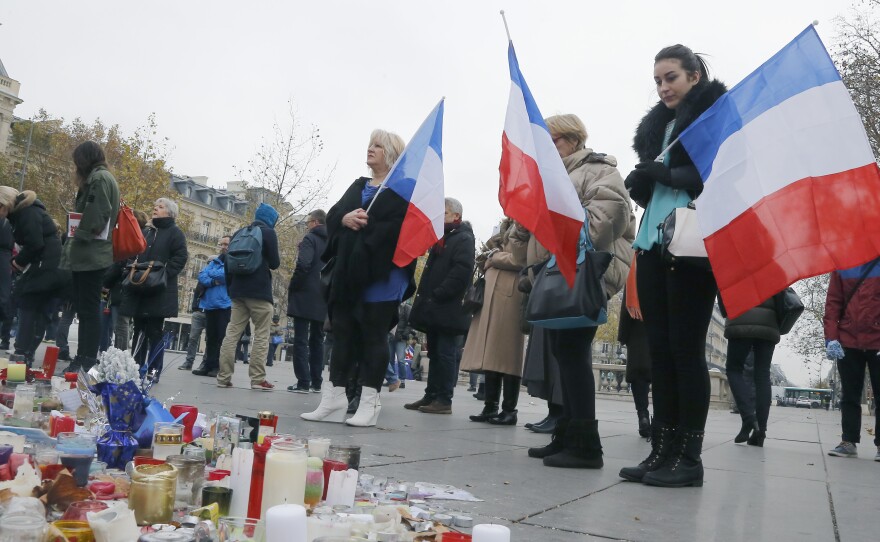 People hold French flags on the Place de la Republique in Paris on Friday. A subdued France paid homage to those killed two weeks ago.