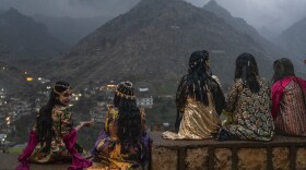 Girls sit on a wall to get a good vantage point of people walking up the mountains with flaming torches and fireworks for Nowruz in Akre, the Kurdish region of Iraq on Friday.
