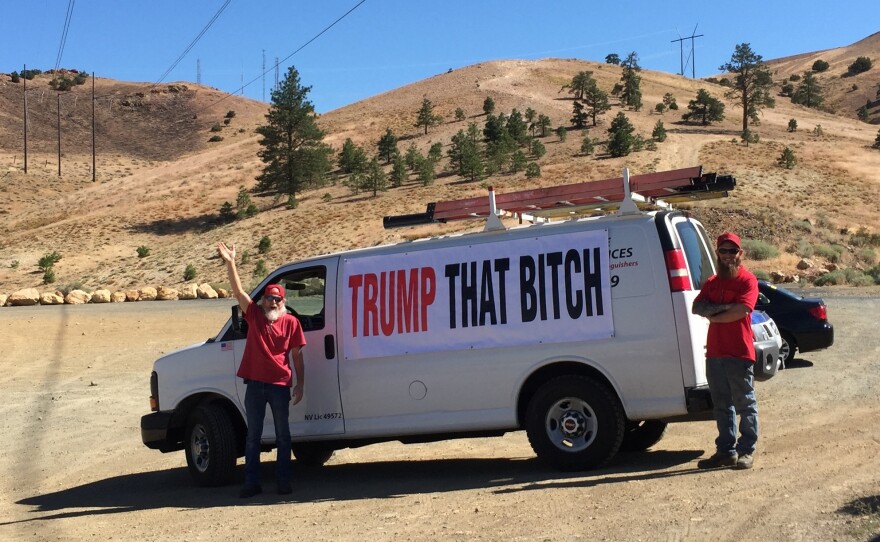 Two men openly display an anti-Hillary Clinton banner with an expletive on it stretched across their white van on the side of a road in Reno, Nev., near a Clinton rally in August.