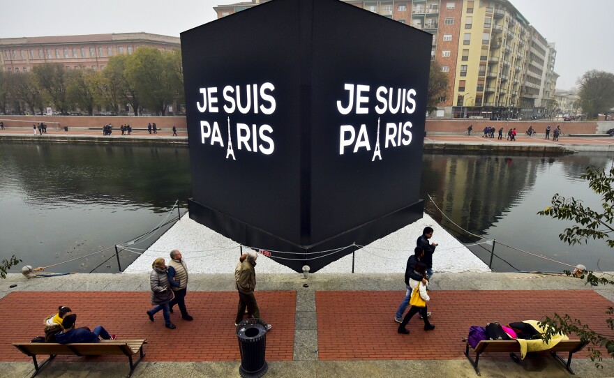 People walk past street placards reading "I am Paris" at the Darsena canal in Milan, Italy.