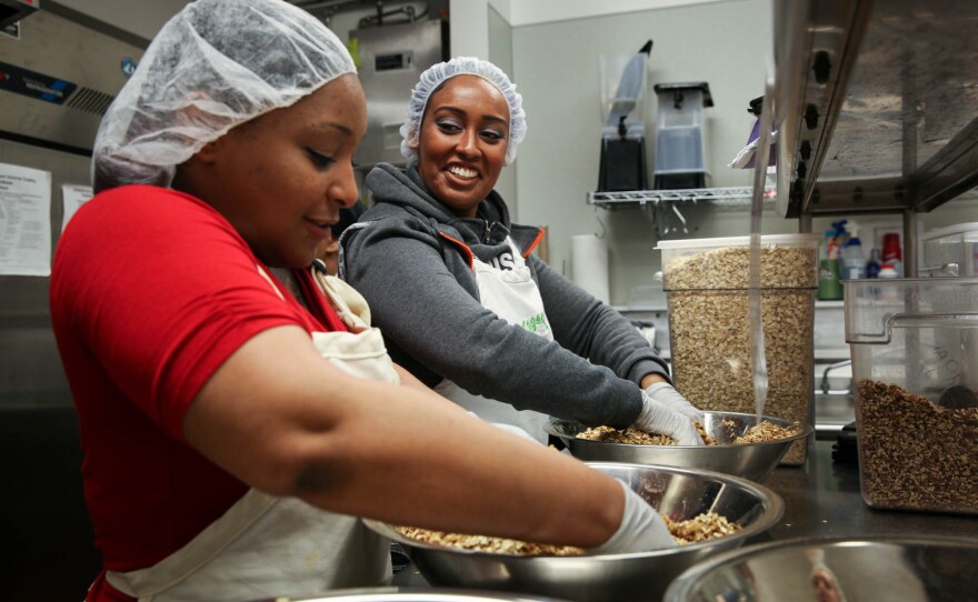 Nikki Yates, a program participant, and Hanna Teklu, a graduate of the program and now a program assistant, mix granola.