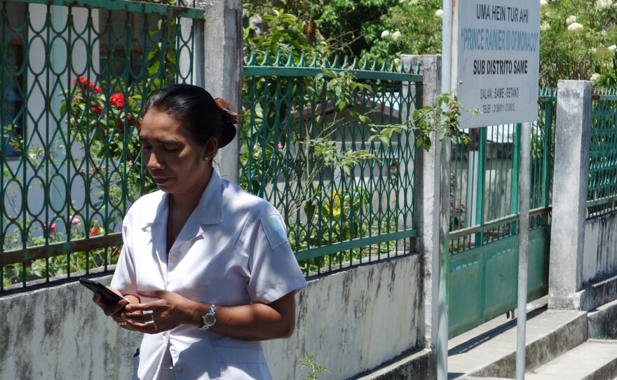 Midwife Mana Justa checks her phone outside the maternity ward in the village Same. The Liga Inan service allows mothers and midwives to send short messages to each other when the mothers have questions.