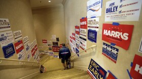 In this Saturday, May 5, 2018 photo, a man passes political posters during the California Republican Party convention in San Diego. 