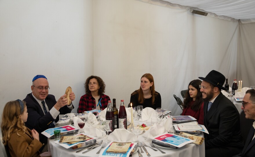 A Ukrainian immigrant, center, listens as the youngest girl from the local Jewish community sings the four questons before the ceremonial meal.