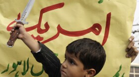 A Pakistani boy holds a dagger before a placard reading "Who is terrorist, America" during a rally Sunday in Lahore, Pakistan, to condemn NATO helicopter attacks on Pakistani troops. Despite new tensions that have arisen from the raid, some observers say the U.S. and Pakistan have little choice but to continue to work together. 