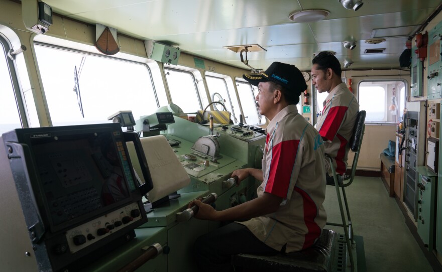 Ferry Capt. Mulyono (left) and a colleague look out the front of the ferry on its way to Lombok. "We serve all the people," Mulyono says.