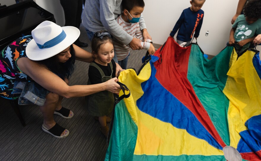 Melisa Alexandra Castro and her daughter, Michelle, 3, play with a parachute with other parents and their children during a musical playgroup program at The Music Therapy Center in Kearny Mesa on Nov. 19, 2022.