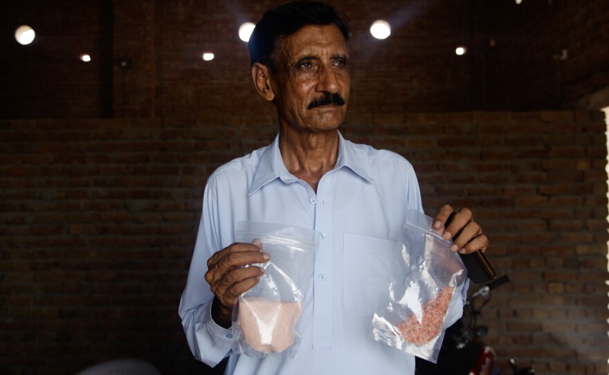Qaisar Mahmood, a small-time Pakistani salt exporter, holds up two bags of pink Himalayan salt ground up to various consistencies. His business has been devastated by the ban on exports to India, and he says it is a bad idea to force companies to label salt as Pakistani, because the country is known as a place of troubles — not fancy salt.
