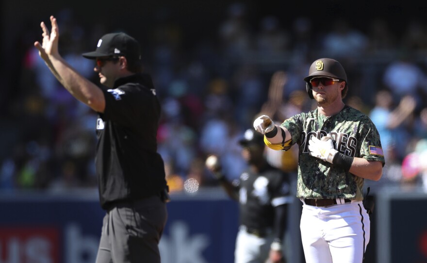 San Diego Padres' Jake Cronenworth, right, points toward the dugout after hitting a double against the Chicago White Sox as umpire Adam Beck calls time in the fourth inning a baseball game Sunday, Oct. 2, 2022, in San Diego.