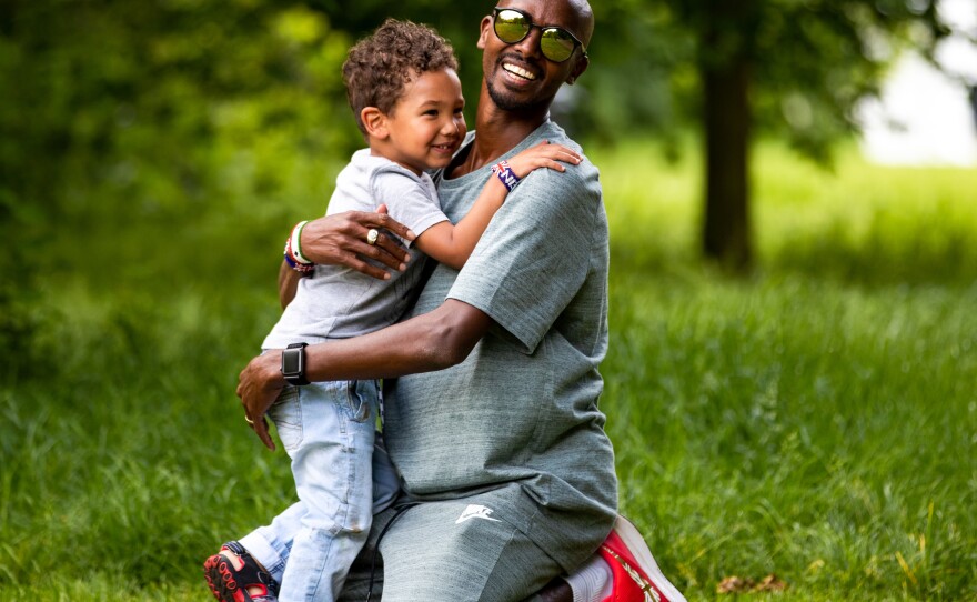 Mo Farah and his son, Hussein, embrace in 2018 as they play in St. James' Park in London, England. Farah says he's known under a false name, and that his real name is Hussein Abdi Kahin.