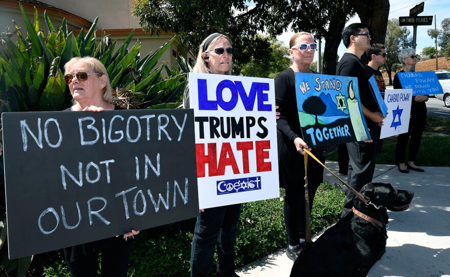 People gathering on a street corner hold signs in support of the victims of the Chabad of Poway synagogue shooting, Sunday, April 28, 2019, in Poway, Calif. A man opened fire Saturday inside the synagogue as worshippers celebrated the last day of a major Jewish holiday.