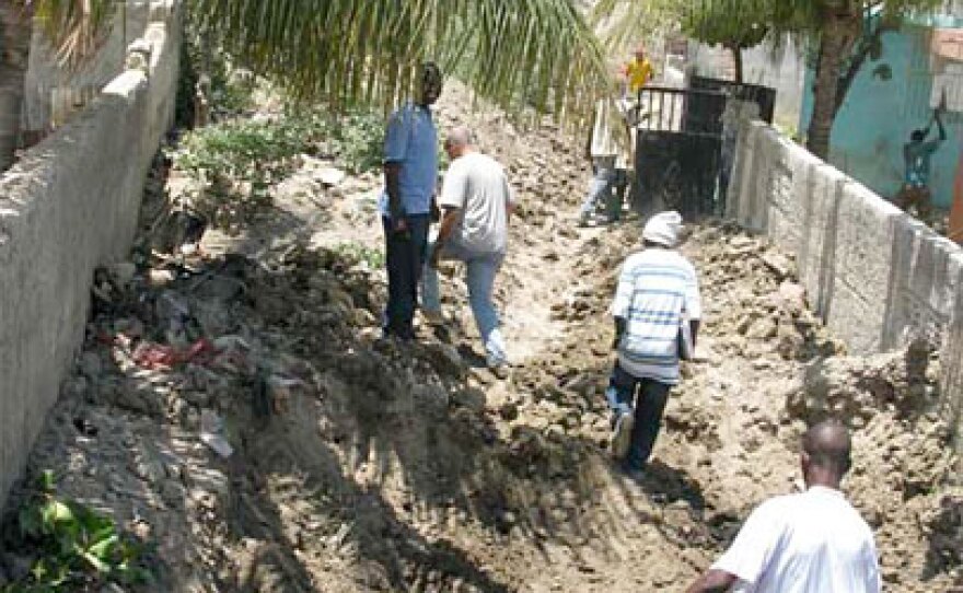 Workers make their way through a street filled with dirt and debris from last year's hurricanes in Gonaives, Haiti.
